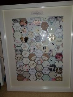 a white frame with lots of magnets and pictures on the inside of it that is covered in hexagonal tiles