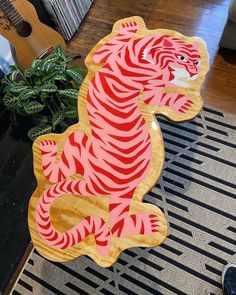 a wooden cut out of a tiger sitting on top of a rug next to a guitar