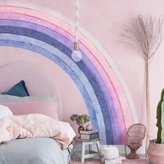 a pink bedroom with a rainbow wall mural