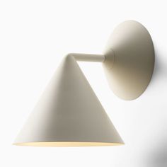 a white wall mounted light on the side of a wall next to a lamp shade