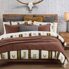 a bed with brown and white comforter in front of a deer skull on the wall