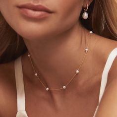 a close up of a woman wearing a necklace and earrings with pearls on the neck