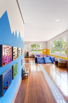 an empty room with wooden floors and brightly colored wall art on the walls, along with children's play areas