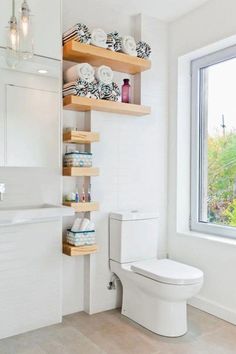 a white toilet sitting in a bathroom next to a window with open shelving above it