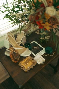 wedding shoes and jewelry on a table with flowers