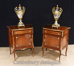 two small wooden side tables with gold vases on top