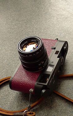 a camera sitting on top of a red leather case