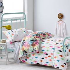 a child's bed with colorful polka dot sheets and pillowcases on it