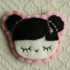 a close up of a stuffed animal on a white surface with pink and black trim