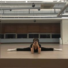 a woman sitting on the floor taking a selfie with her cell phone in an empty room