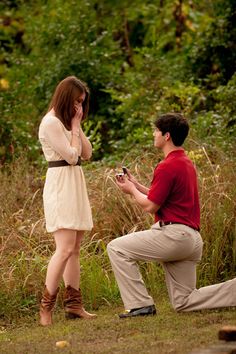 a man kneeling down next to a woman holding a cell phone in front of her