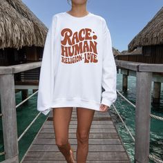 Promote unity and love with our "Race Human, Religion Love" sweatshirt. This cozy and inspiring sweatshirt is made from soft, high-quality fabric, ensuring warmth and comfort. Its meaningful message and stylish design make it perfect for any casual setting. Wear this sweatshirt to spread a message of inclusivity and harmony while staying comfortable and chic. Material: 50% cotton and 50% polyester Fabric Weight: Medium Heavy Fit: Loose fit Neck: Crew Sustainably sourced materials for an eco-frie Long Sleeve Screen Print Sweatshirt In Athleisure Style, Athleisure Long Sleeve Sweatshirt With Screen Print, White Letter Print Sweater In Athleisure Style, Athleisure White Sweater With Letter Print, Long Sleeve Sweatshirt With Slogan For Leisure, Crew Neck Hoodie With Slogan For Loungewear, White Graphic Print Sweats For Loungewear, Relaxed Fit Slogan Sweatshirt For Leisure, Leisure Long Sleeve Sweatshirt With Slogan