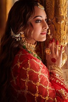 a woman in a red and gold outfit with her hands on the side of her face