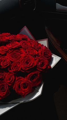 a bunch of red roses sitting on top of a white box in the back seat of a car