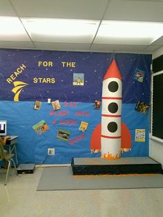 a room with a rocket ship on the wall and desks in front of it