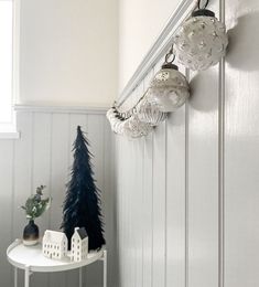 a christmas tree is hanging on the wall next to a white table with ornaments in it