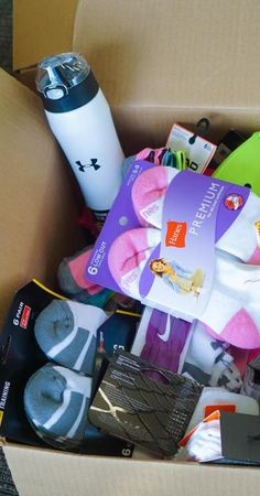 an open cardboard box filled with assorted items like socks, coffee mug and more