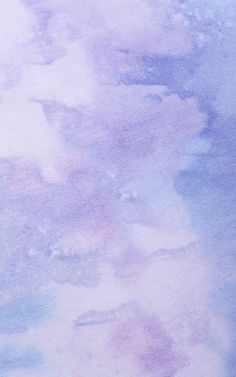 an airplane is flying in the sky over some watercolor paint on paper that looks like it has been dyed purple and blue