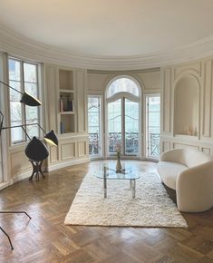 a living room filled with white furniture and lots of windows on top of wooden floors