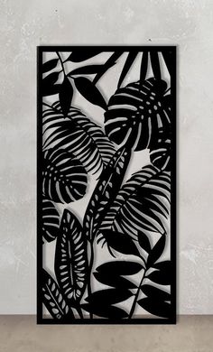 a black and white paper cut art piece with leaves on it, in front of a wall