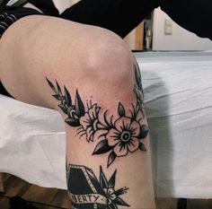 a woman's leg with black and white flowers on her left side, next to a bed