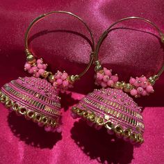 Beautiful pink and gold jhumka earrings. These earrings are light weight and can easily be dressed up or down. You can pair this with traditional wear. These Jhumkas have a vivid pink color which is intensified by the beautiful gold. These earrings also have beautiful beading. Cheap Bohemian Dangle Jhumkas, Cheap Bohemian Jhumkas For Diwali, Cheap Festive Jhumkas With Latkans, Affordable Wedding Jhumkas For Diwali, Chandbali Earrings With Bells For Festivals, Traditional Festive Earrings With Bells, Traditional Festive Bell Earrings, Elegant Pink Chandbalis For Festive Occasions, Pink Chandbali Bridal Earrings Gift