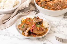 two plates with meat and vegetables on them next to a bowl of mashed potatoes