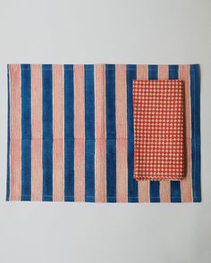 two red and blue striped placemats sitting next to each other on a white surface