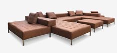 a brown couch and ottoman sitting next to each other on a white surface with pillows