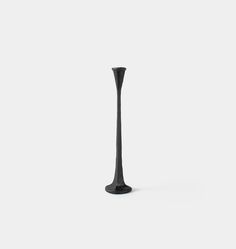 a tall black vase sitting on top of a white table