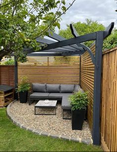 an outdoor seating area with wooden fence and plants on the ground, surrounded by gravel