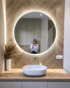 a woman taking a selfie in front of a bathroom mirror with the lights on