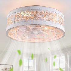 a white ceiling light hanging from the ceiling in a room with green leaves flying around