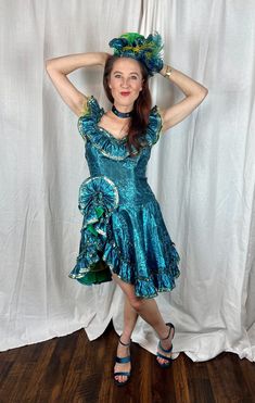 a woman in a blue dress posing for the camera with her hands on her head