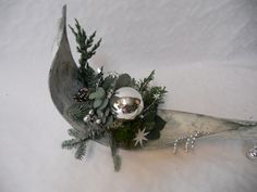 a silver vase filled with flowers and greenery sitting on top of snow covered ground