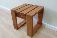 a wooden stool sitting on top of a hard wood floor next to a white wall