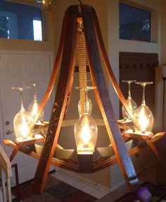 a chandelier made out of wine glasses and wooden planks with lights on them