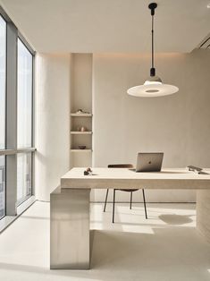 a white table with a laptop on it in front of a large window and some bookshelves