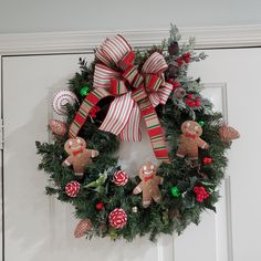 a christmas wreath with gingerbreads, candy canes and ornaments hanging on the front door