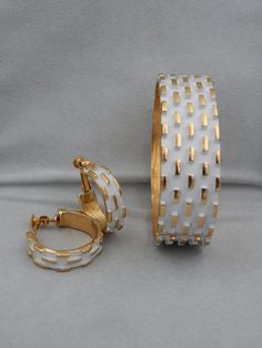 "Napier got it right in their 1973 ad for this line of jewelry \"Napier Is Groovier.\" Something about the stark white against the vibrant gold-plate makes these vintage Napier pieces art-like. The raised rectangular design on the cuff bracelet and earrings draw attention to the shape and flow of each piece. Napier designer Francis Fujio was the artistic genius during this era. His designs took the hot color for 1973, which was white, and transformed it into timeless, classical costume jewelry t Collectible White Jewelry, White Hoop Jewelry For Formal Occasions, Vintage White Metal Jewelry, Collectible White Metal Jewelry, White Metal Hoop Earrings For Anniversary, Anniversary White Metal Hoop Earrings, White Retro Jewelry For Anniversary, Retro White Jewelry For Anniversary, Vintage White Hallmarked Jewelry