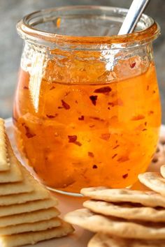 a glass jar filled with liquid next to crackers and crackers on a plate