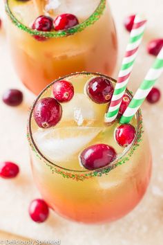 two glasses filled with liquid and topped with cherries, candy canes and sprinkles