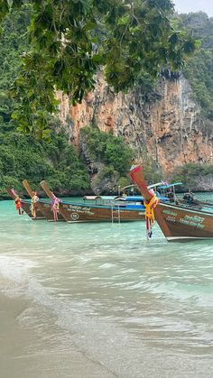 there are many boats in the water near each other on the beach and one boat is tied to the shore