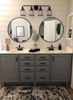 a bathroom with two round mirrors above the sinks and an area rug on the floor