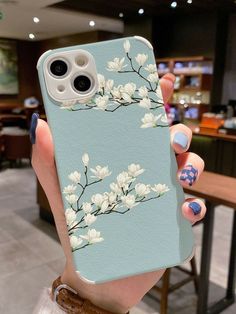 a woman holding up her phone case with flowers on it