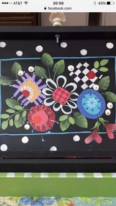 an artistic painting on the side of a wooden box with flowers and leaves painted on it