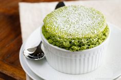 a green tea souffle on a white plate with a fork and spoon next to it