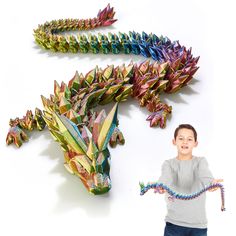 a young boy standing next to two colorful paper dragon sculptures on a white background, one is holding a string