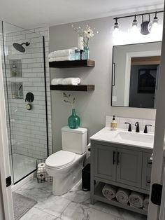 a white toilet sitting next to a walk in shower under a bathroom mirror above a sink