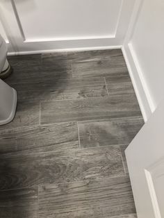 a white toilet sitting next to a wooden floor